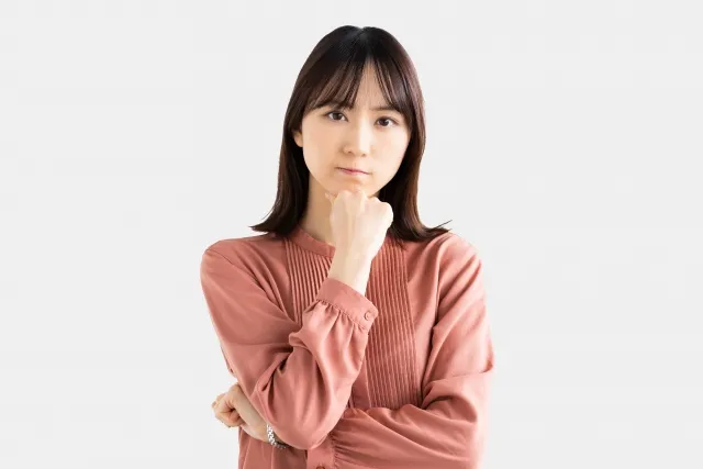 右の拳を顎に当てながら考えている表情の女性