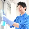 窓の清掃をしている青い作業着を着た男性作業員