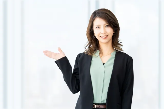 右の手のひらを差し出しているオフィスカジュアルの女性